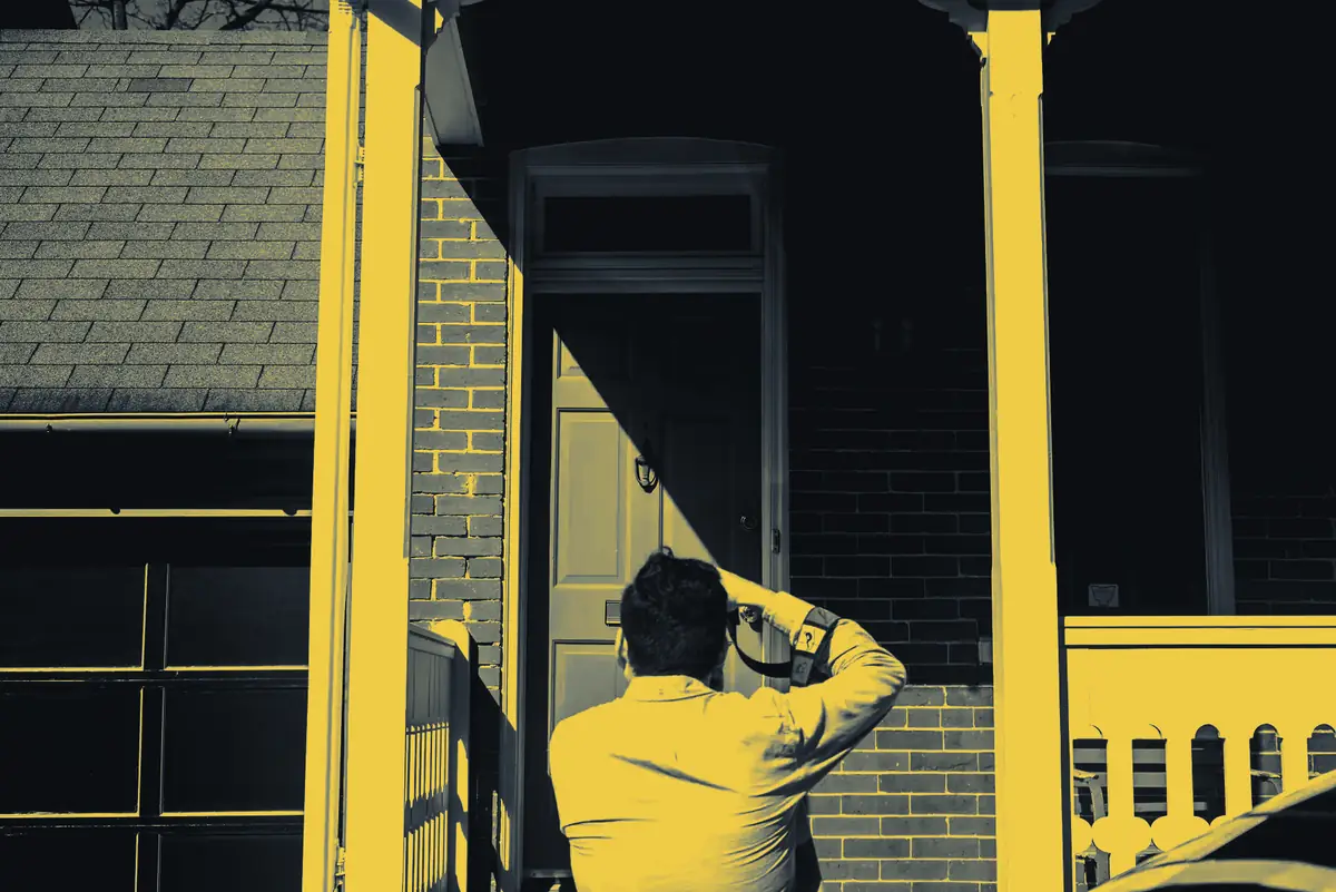 A Brannock estimator photographing storm damage on a brick house for an insurance claim