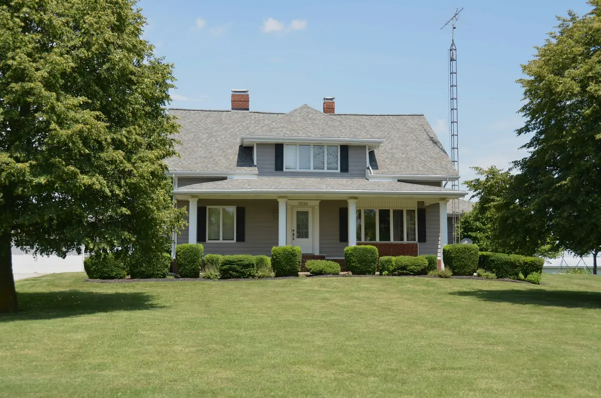 Large white house with a long porch on a green lawn
