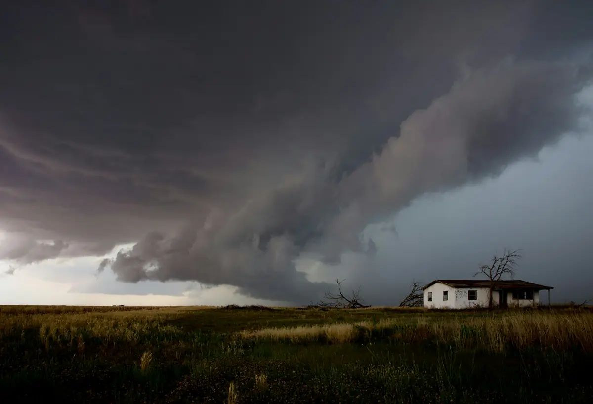 Dark storm clouds rolling over a lone house on open land